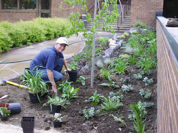 student kneeling with plants